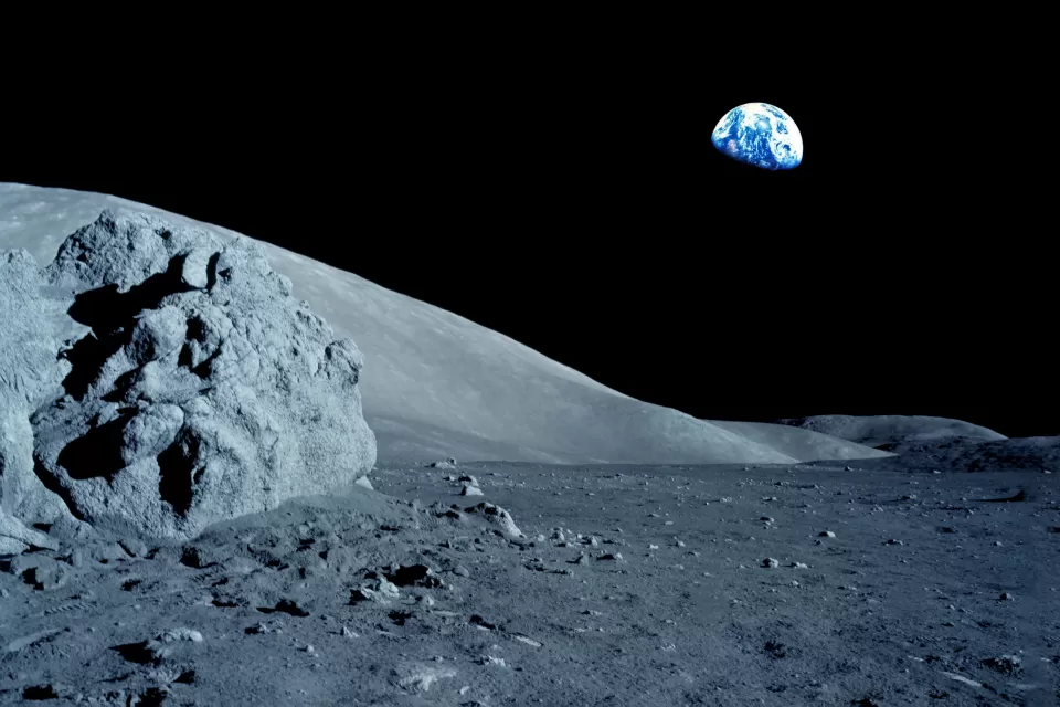 Gray moon surface with black sky and Earth in the background.